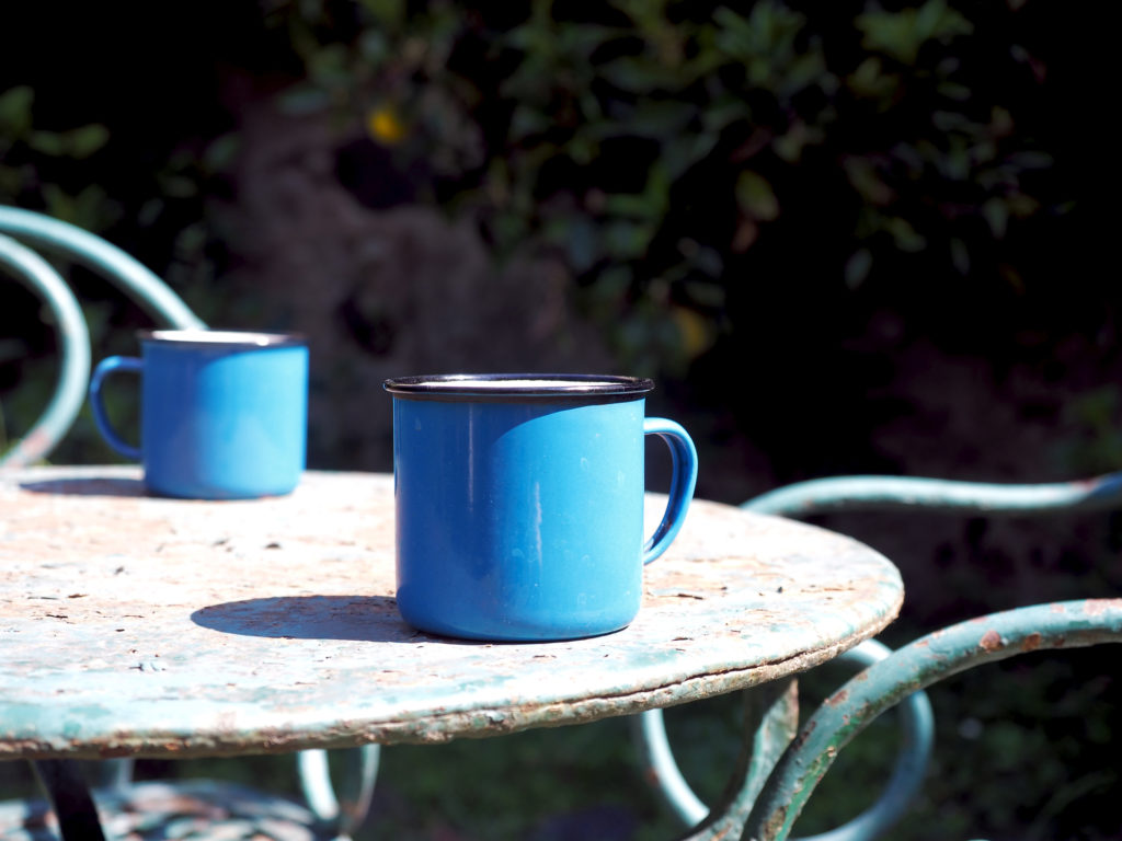 A table and chair set that is badly rusted, with two mugs resting on top.