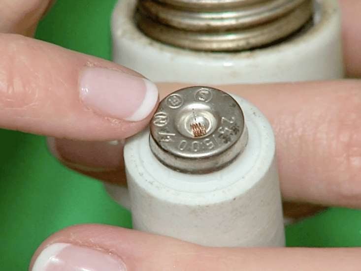 A person showing a blown fuse from a fuse board