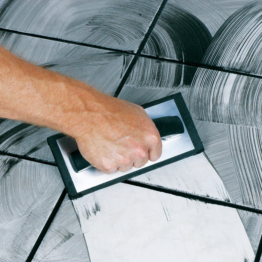 A grout float being used to work the grout in to the tile