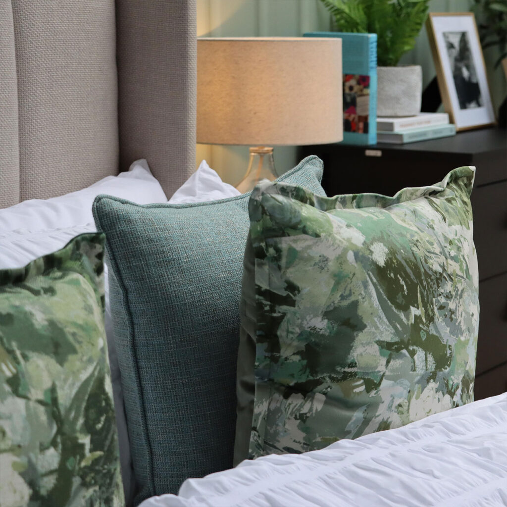 Floral green cushions lying next to each other on a bed