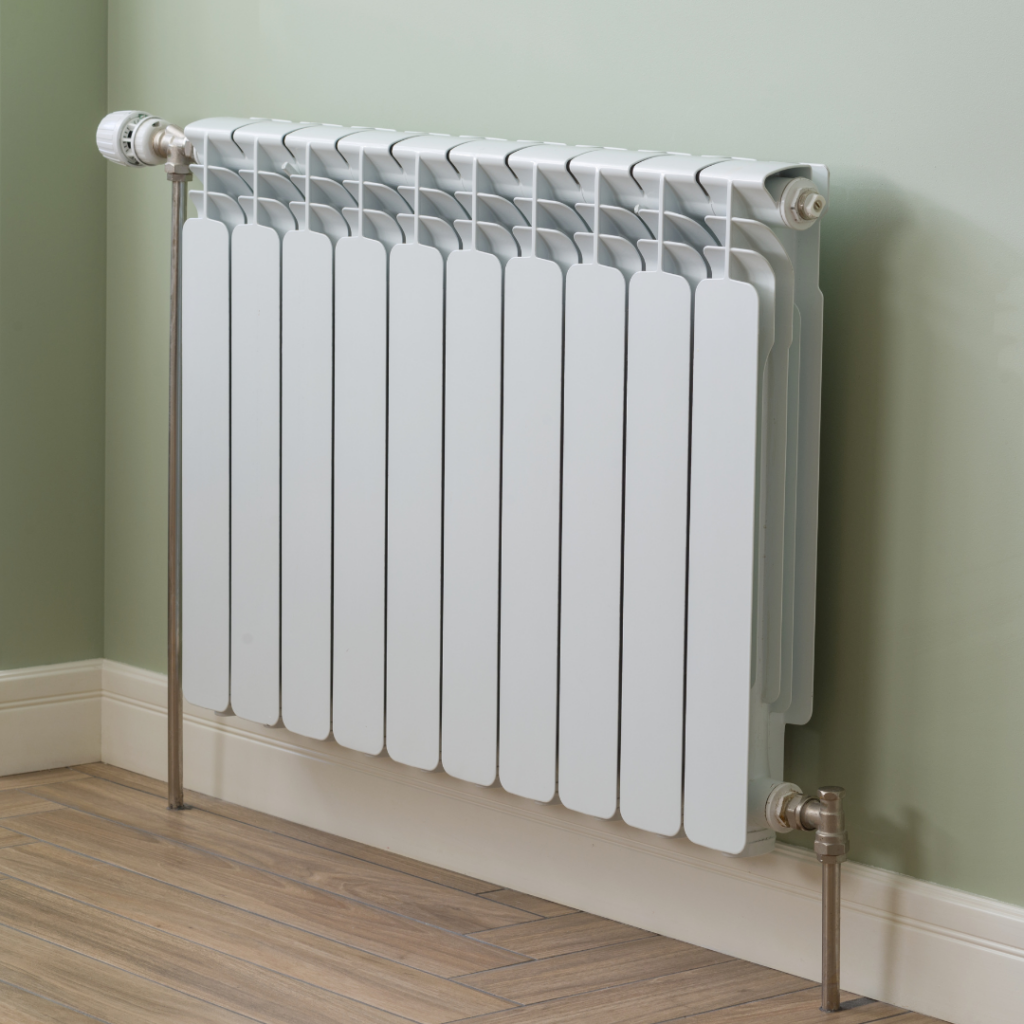 White radiator on a wood floor in a room with green walls