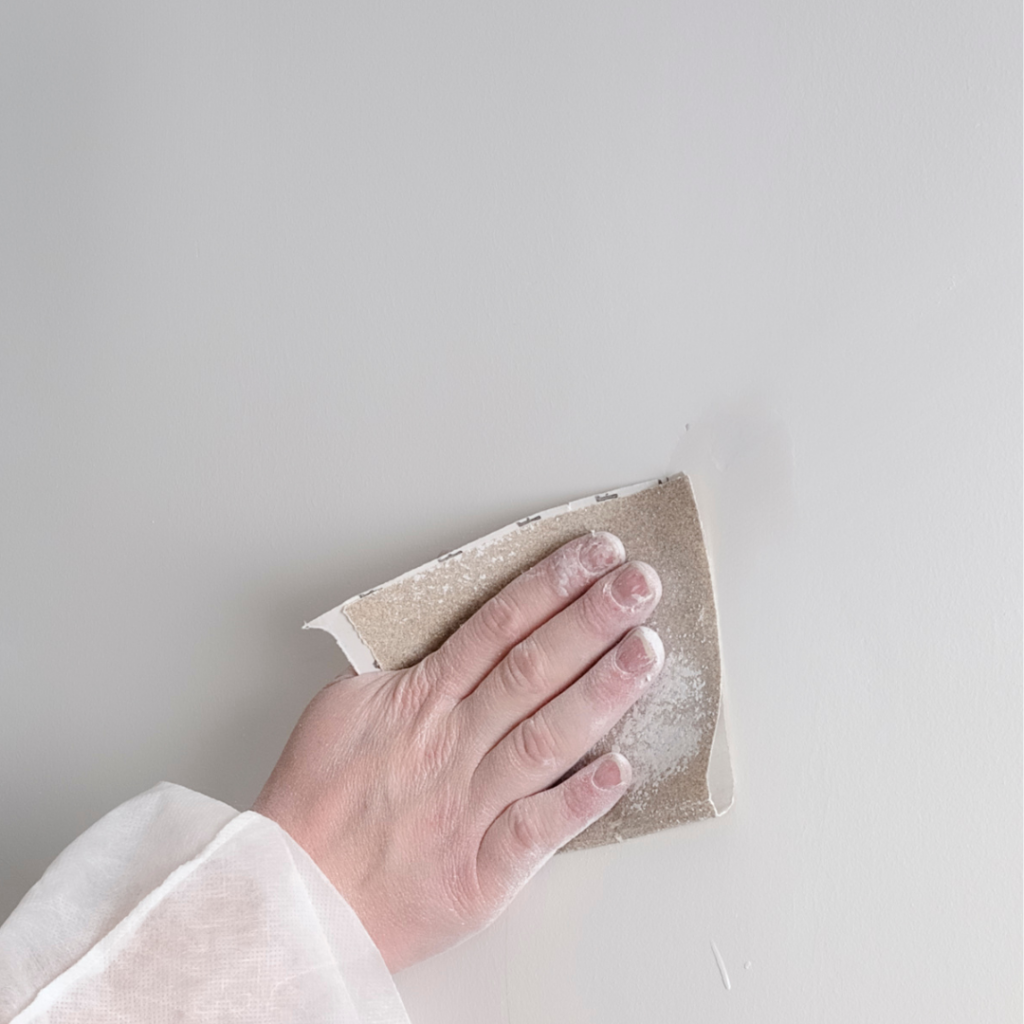 White wall being sanded with sandpaper