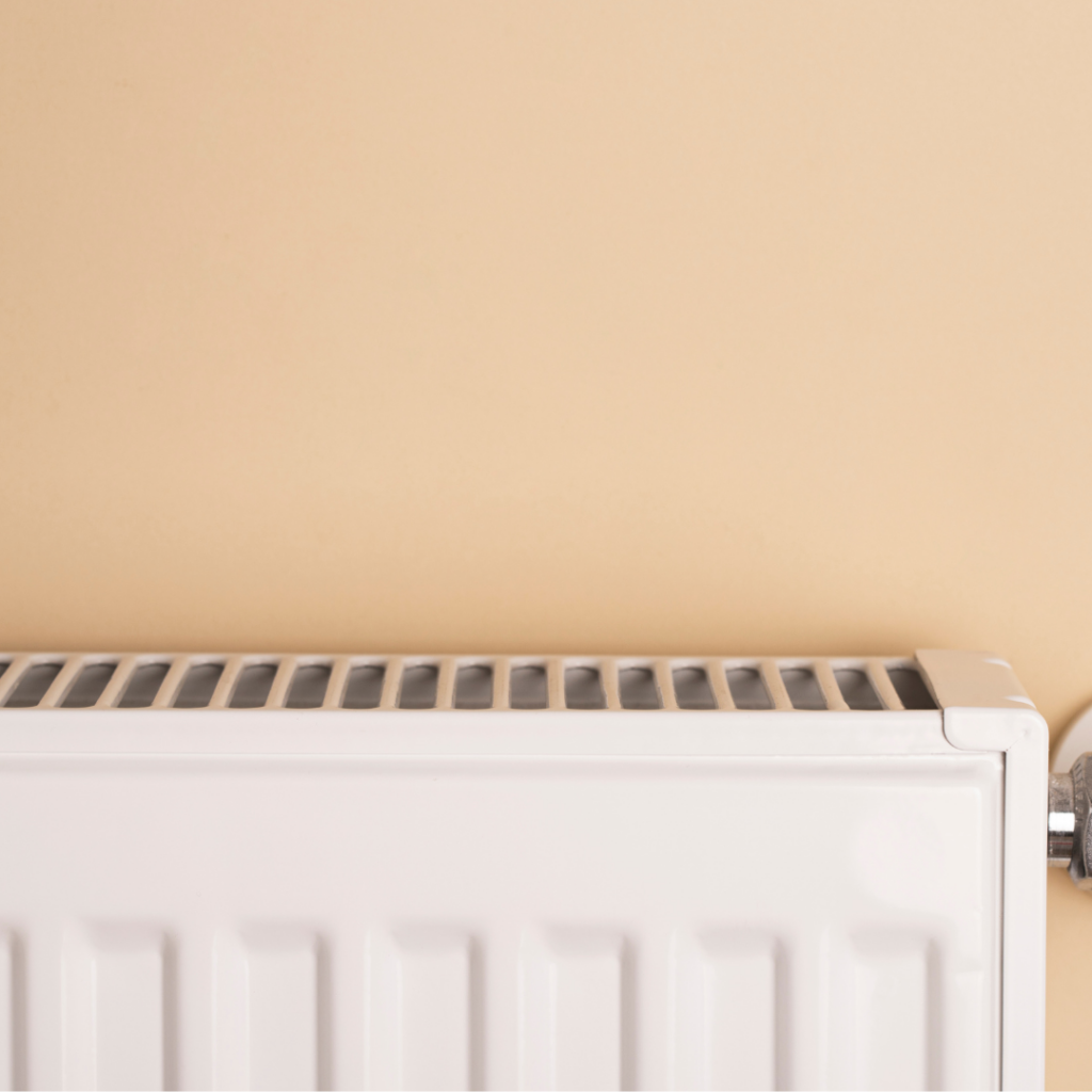 A white radiator in a room with beige walls